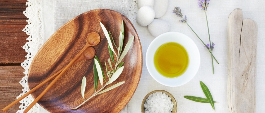 Plateau en bois avec cuillères, feuilles d’olivier, huile, sel de mer et lavande