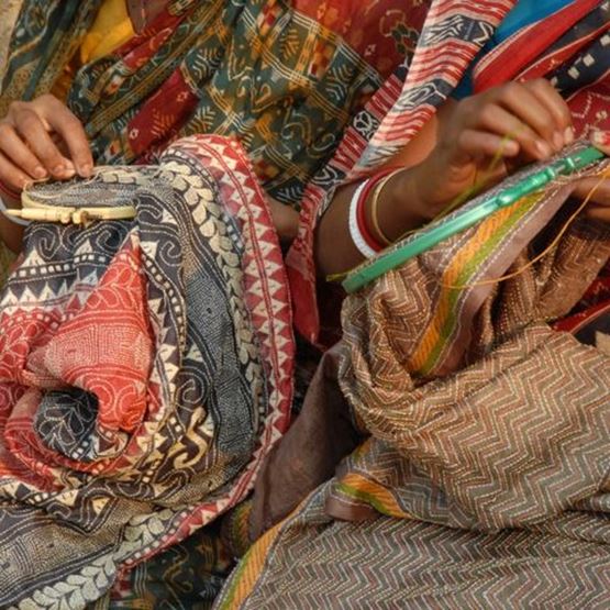 Personnes brodant des motifs traditionnels sur des tissus avec un métier à tisser.