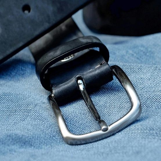 gros plan sur une boucle de ceinture en cuir posée sur un jean.