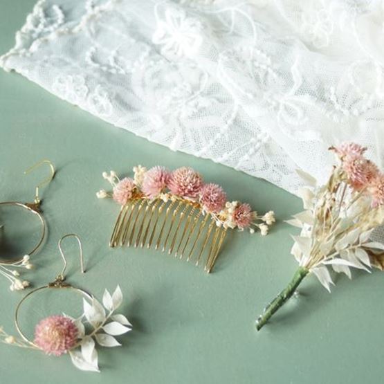 Bijoux ornés de fleurs séchées : peigne, boucles d’oreilles et boutonnière, posés sur un tissu en dentelle.
