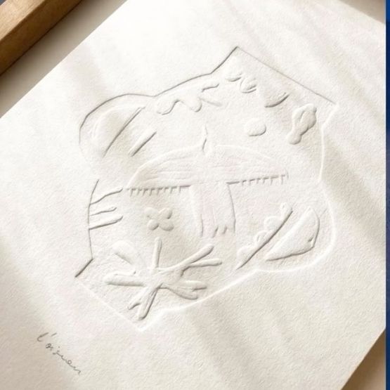 Feuille embossée avec motifs en relief représentant un paysage stylisé.