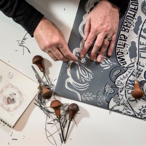 Gravure artisanale en cours de réalisation avec outils de linogravure.