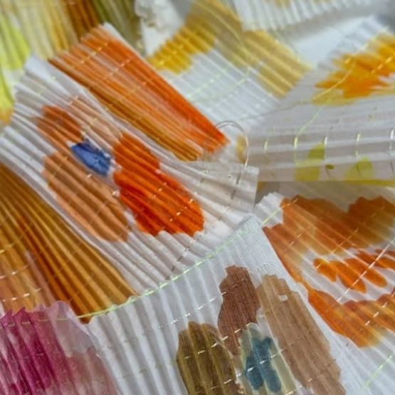 Gros plan sur tissu plissé aux motifs colorés peints à la main.