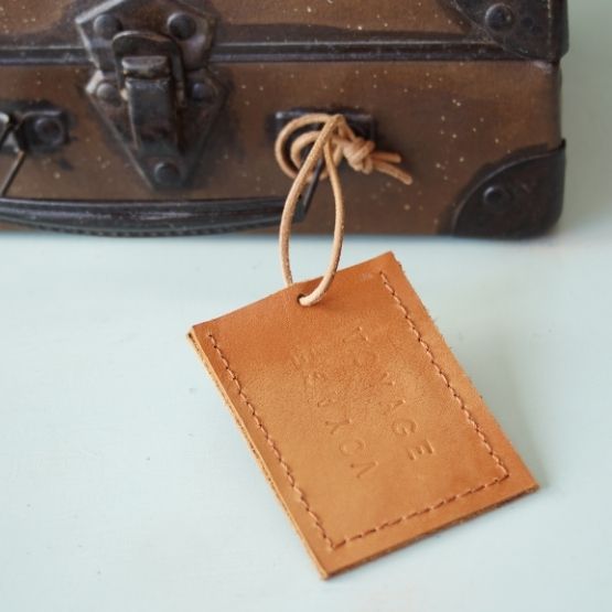 Étiquette en cuir cousue à la main attachée à une valise vintage.