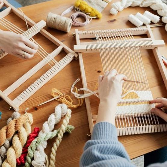 Tissage terminé sur un métier à tisser avec fils de laine jaune et blanc.