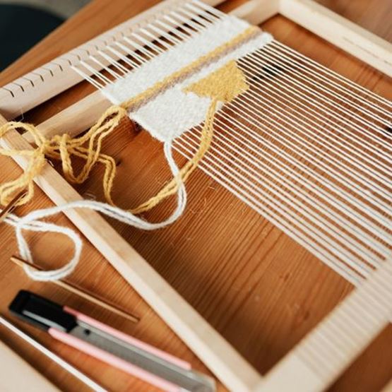 Atelier de tissage avec deux personnes utilisant des métiers à tisser à main.