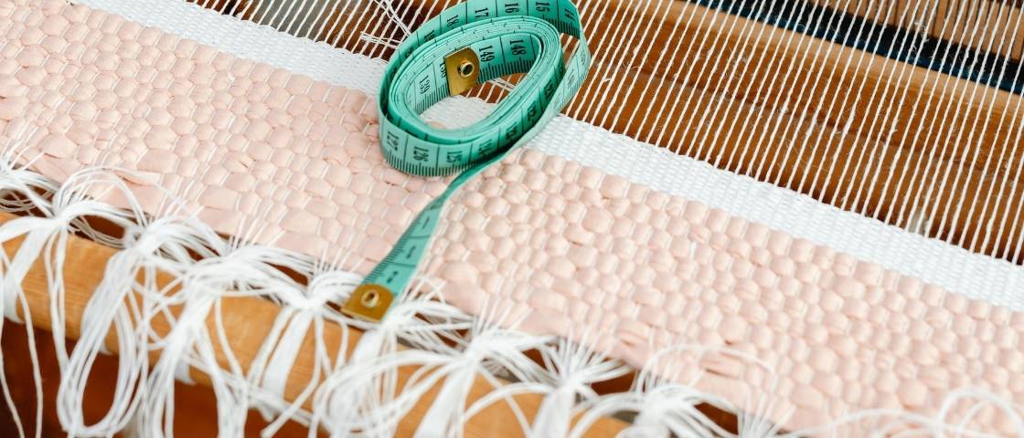 Tissage peyote en perles bleues sur un métier à tisser artisanal.