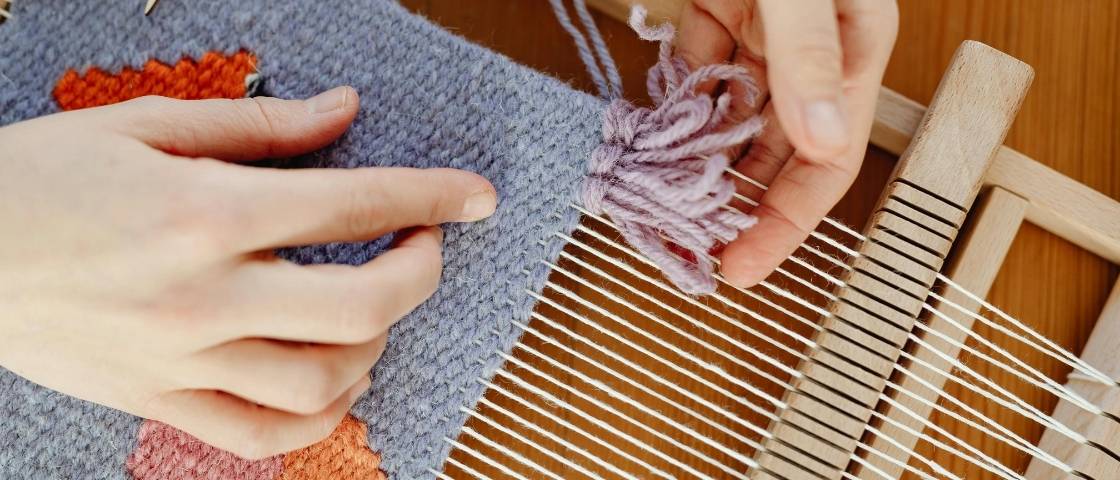 Tissage en cours avec navette rouge sur métier en bois traditionnel.
