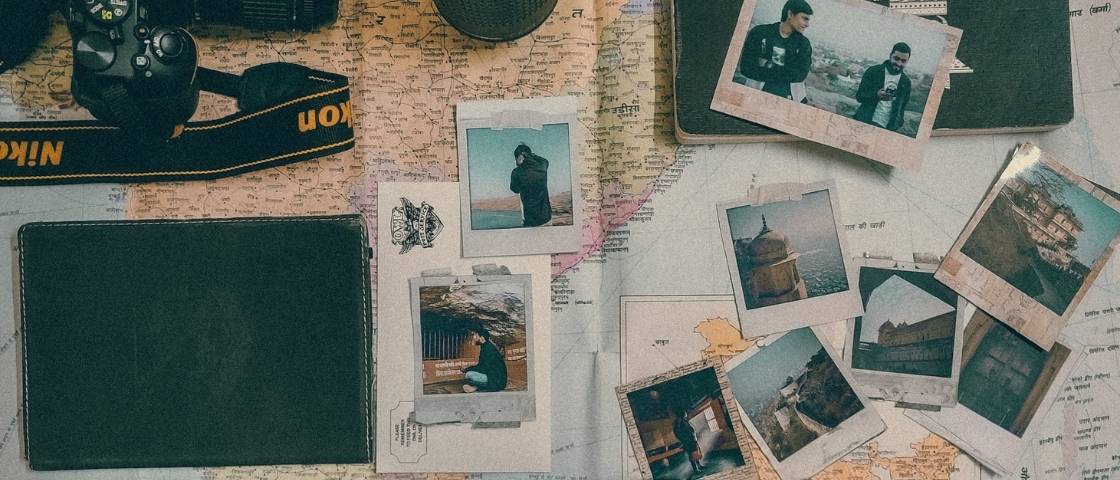 Photos de voyage de style polaroid posées sur une carte du monde avec un appareil photo reflex.