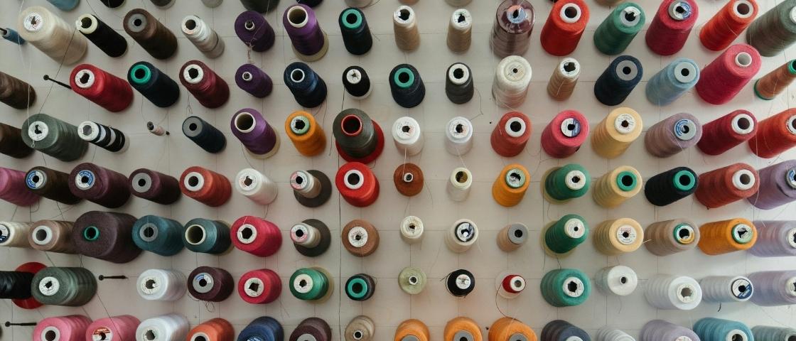 Bobines de fils de couleurs variées accrochées à un mur