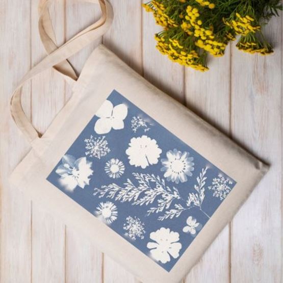 Tote bag beige décoré d’un motif cyanotype de fleurs blanches sur fond bleu.