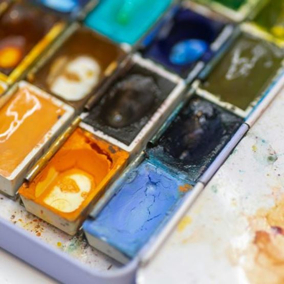 Palette d’aquarelle utilisée, avec des couleurs intenses et des traces de peinture.