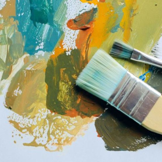 Pinceaux posés sur des taches de peinture gouache multicolore.