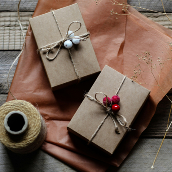 Deux boîtes cadeaux en kraft décorées de ficelle et de baies rouges et blanches.