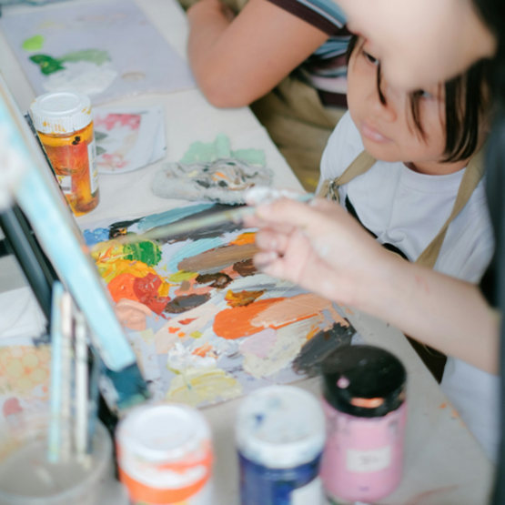 Enfant concentré sur une palette de peinture lors d’un atelier artistique.