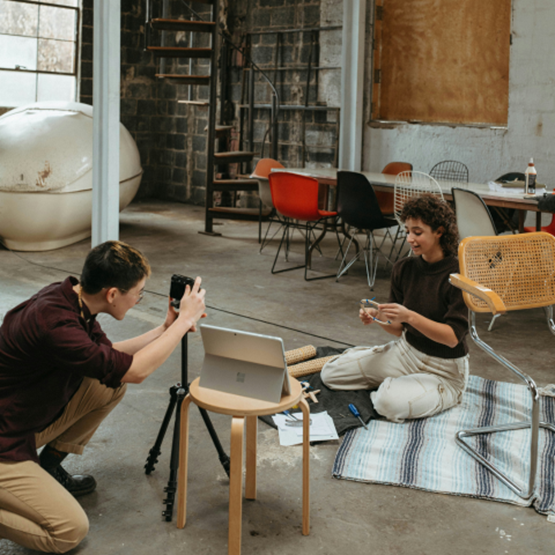 Deux personnes enregistrent une vidéo dans un atelier avec un smartphone et un trépied.