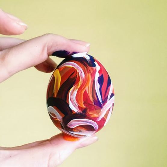 Œuf de Pâques peint à la main avec des motifs colorés rouges, blancs et jaunes.