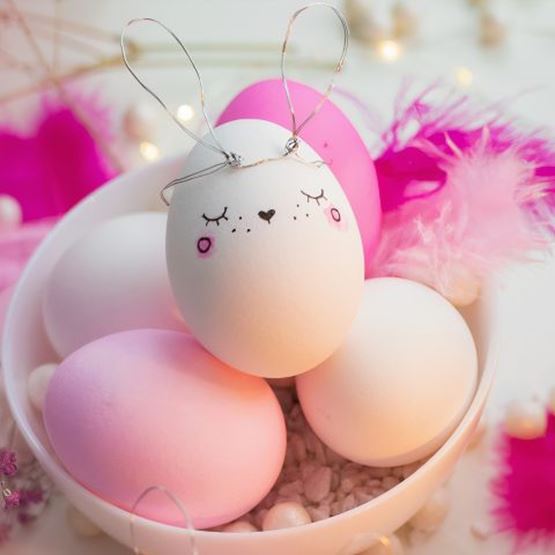 Œuf de Pâques décoré comme un lapin avec des traits dessinés et des oreilles en fil de fer.