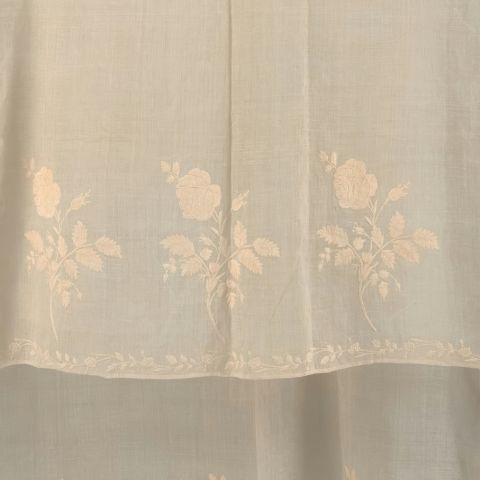 Tissu léger beige orné de broderies florales ton sur ton.