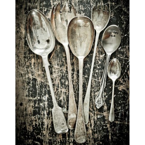 Ensemble de cuillères anciennes en métal posées sur une table usée.
