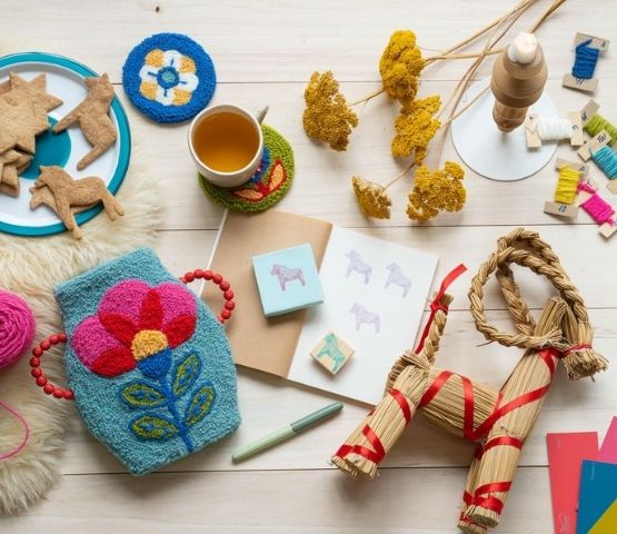 Table de création avec punch needle, gâteaux en forme de chevaux et objets en paille.