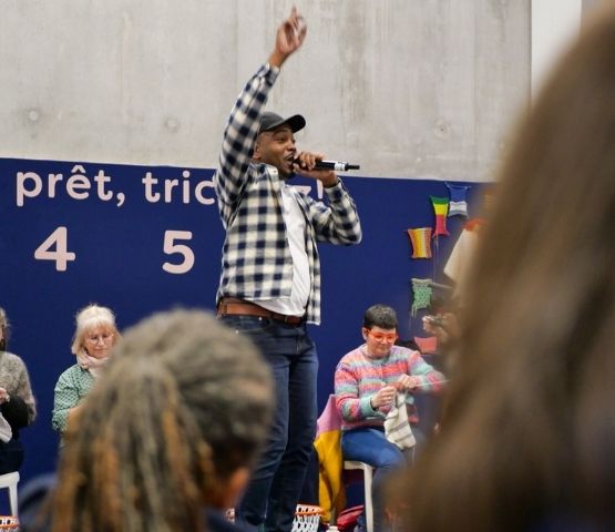 Animateur du concours Speed Knitting sur scène, encourageant les participants pendant l’épreuve.