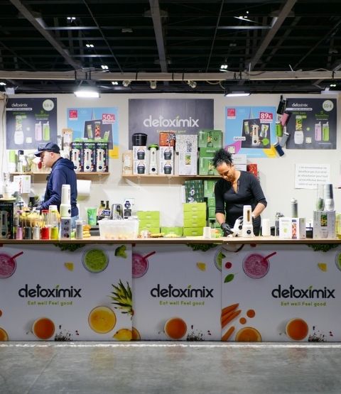 Stand Detoximix avec blenders et bouteilles de jus en démonstration.