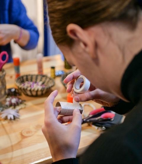 Jeune femme manipulant un rouleau de masking tape lors d’un atelier créatif.