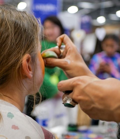 Fille en train de se faire maquiller le visage lors d’une animation.