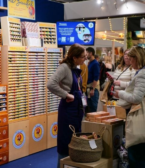 Stand de fils à broder très colorés avec vendeuse en discussion avec une cliente.