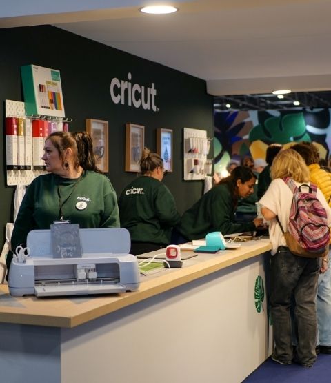Stand Cricut avec démonstrations de machines de découpe et file d’attente de visiteurs.