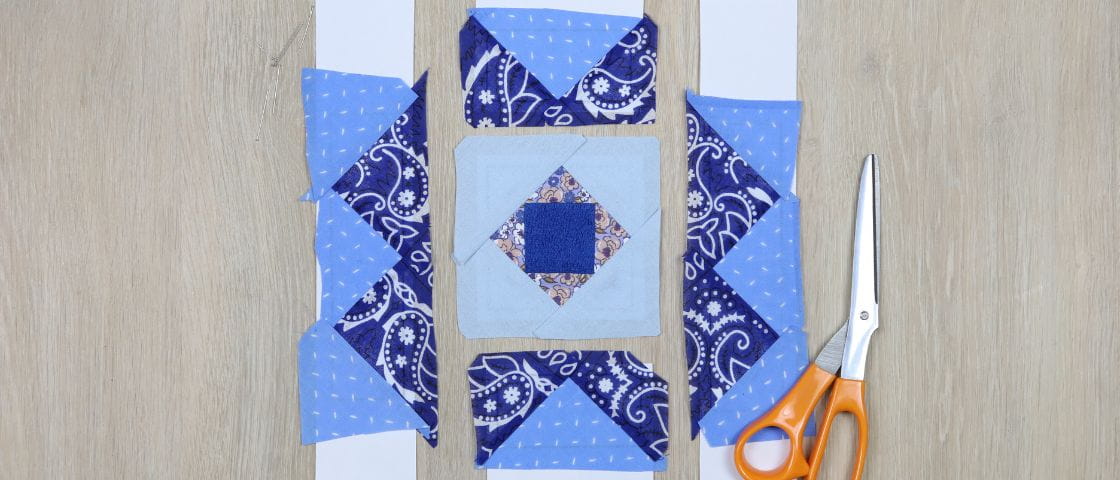 Matériel nécessaire pour apprendre à coudre un patchwork : tissus bleu, ciseaux et patron