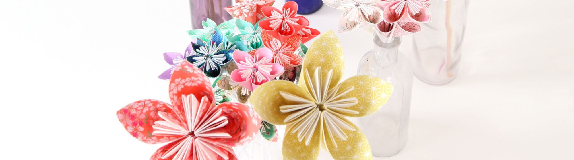 Plusieurs bouquets de fleurs colorées en origami dans des vases