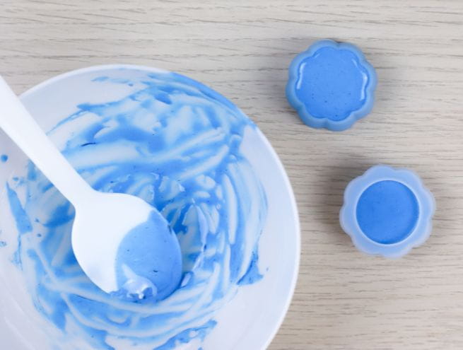 Pâte bleue Jesmonite mélangée dans un bol et coulée dans des moules en forme de fleurs.