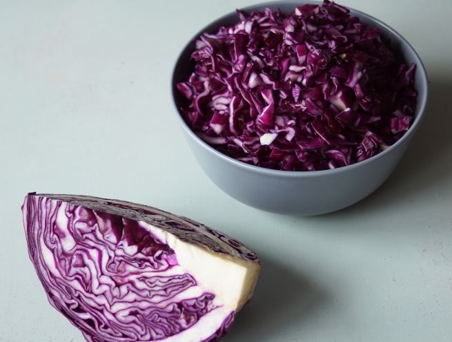 Chou rouge coupé en petits morceaux dans un bol, prêt à être utilisé pour une encre naturelle.