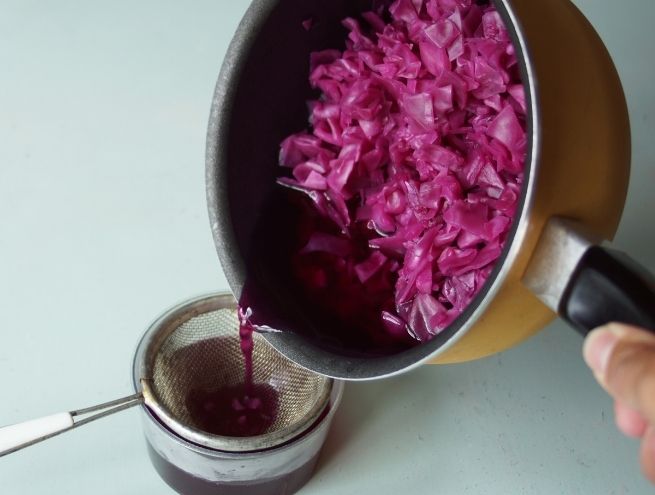 Filtration du chou violet cuit pour récupérer le jus coloré.
