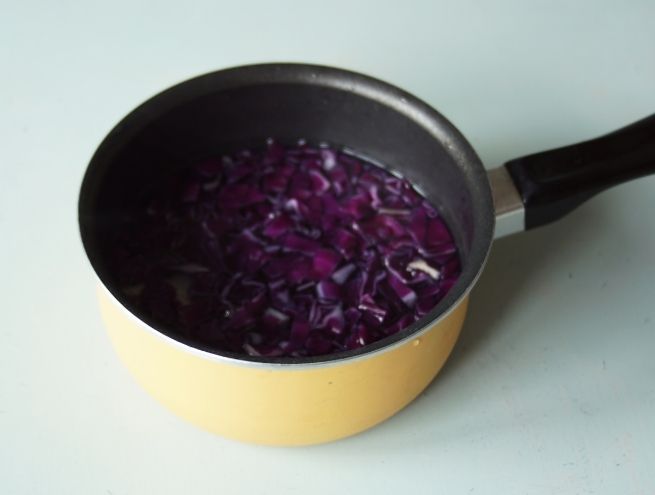 Chou rouge en morceaux baignant dans l’eau au fond d’une casserole jaune.