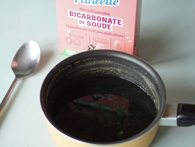 Liquide foncé extrait du chou avec boîte de bicarbonate de soude à l’arrière.