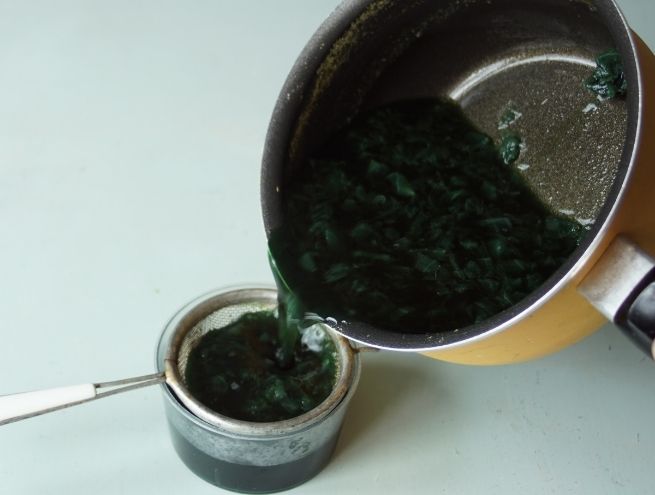 Étape de filtration du mélange vert foncé obtenu à partir de chou et de bicarbonate.