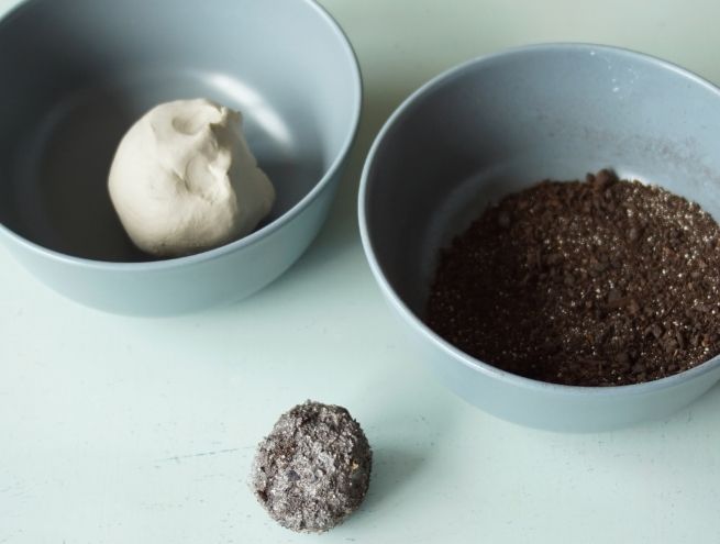 Boule d'argile modelée à côté de terre et d'une boule enrobée.