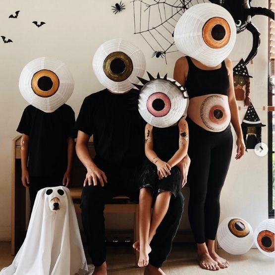 Famille déguisée avec des lanternes en forme d’yeux géants pour Halloween.