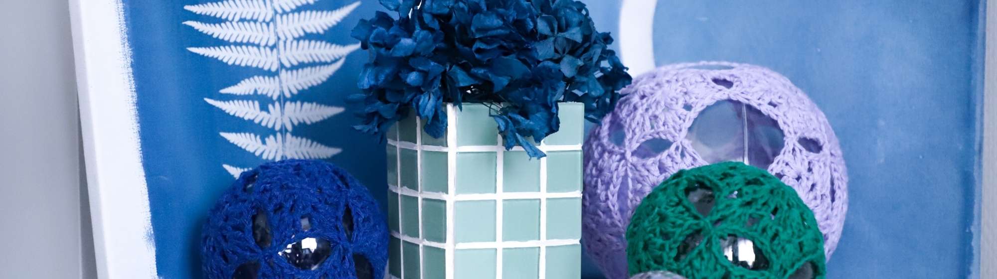 Vase mosaïque terminé, exposé avec des décorations faites main et des fleurs.