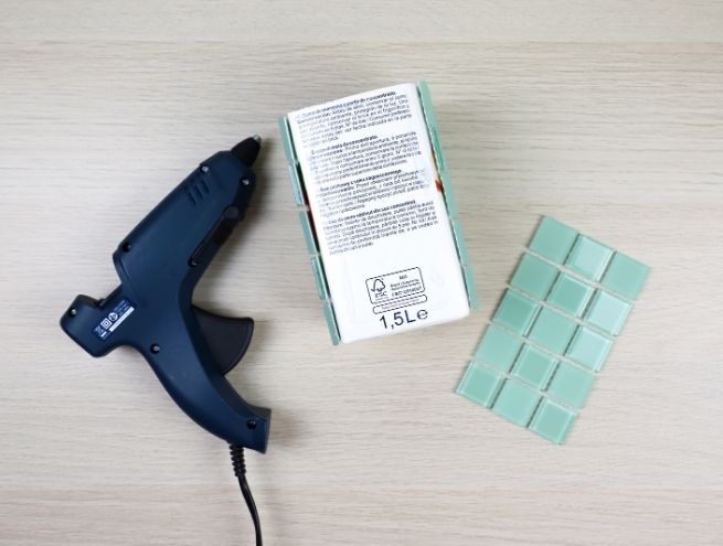 Collage des carreaux de mosaïque sur la brique à l’aide d’un pistolet à colle.