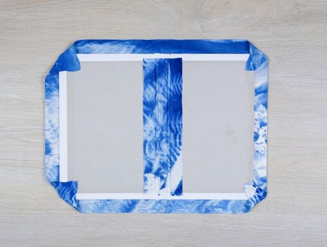 Étape de renfort intérieur du carnet avec colle, pinceau et plioir.