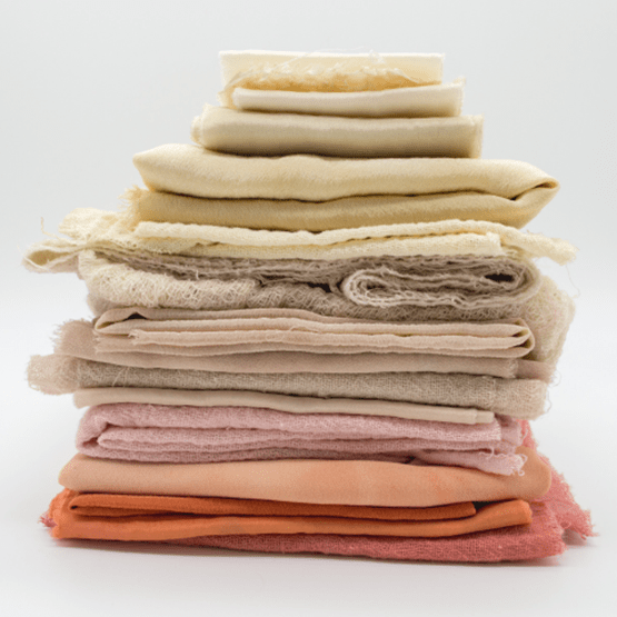 Pile de tissus rose, jaune, orange et beige